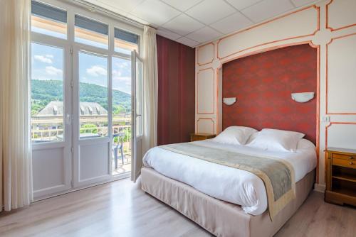 a bedroom with a large bed and a large window at Logis Hotel Le Sablier du Temps in Argentat