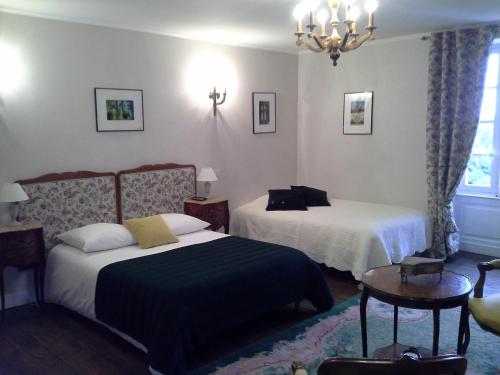 Habitación de hotel con 2 camas y lámpara de araña. en Le Logis De Ruelle, en Ruelle-sur-Touvre