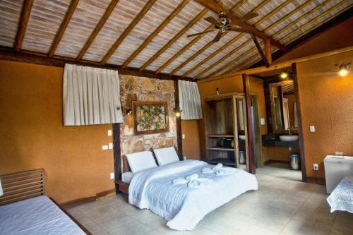 a bedroom with a large bed and a bathroom at Rancho Cipo Pousada in Serra do Cipo