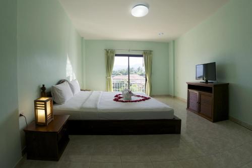 - une chambre avec un grand lit et une télévision dans l'établissement PTK Residence, à Chaweng