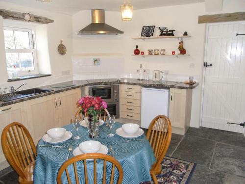 a kitchen with a table with a blue table cloth at Y Bwythyn at Henfaes in Rhydymain