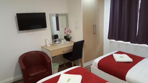 a hotel room with a desk and a bed at Heathrow Travellers Hub in Hounslow