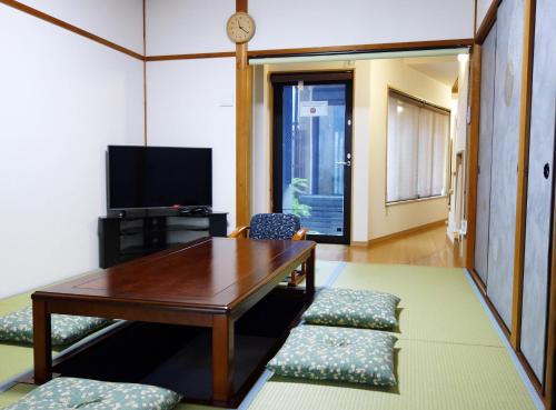 ein Wohnzimmer mit einem Tisch und Stühlen sowie einem TV in der Unterkunft 君の家 東寺 in Kyoto