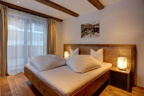 een slaapkamer met een bed met witte kussens en een raam bij Chalet Bella in Pettneu am Arlberg