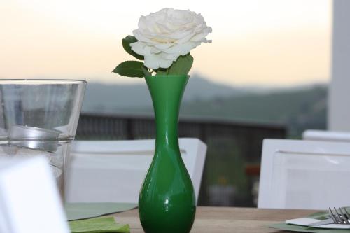 a green vase with a white flower in it on a table at Locanda ai Capitelli snc di fiumicetti andrea in Soave