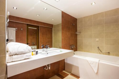 een badkamer met een wastafel en een badkuip en een bad bij Rilets Resort & Spa in Rilski Manastir