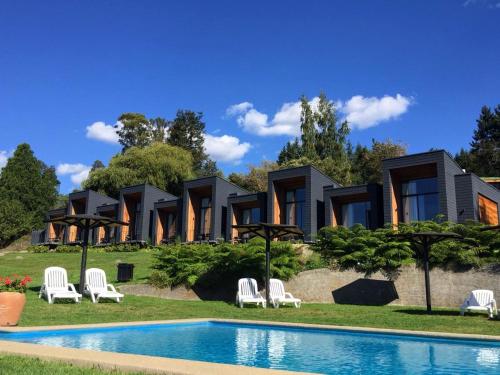 a house with a swimming pool in front of it at Hotel y Cabañas El Parque in Villarrica