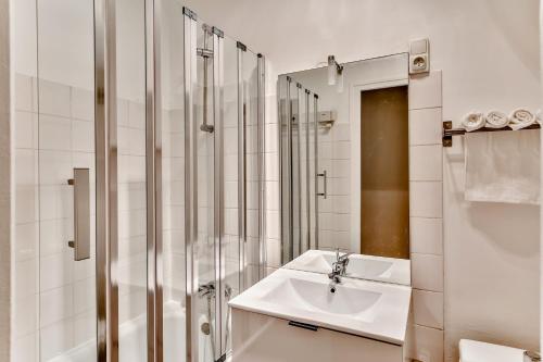 une salle de bain blanche avec un lavabo et une douche dans l'établissement Love Nest in Saint-Michel, à Paris