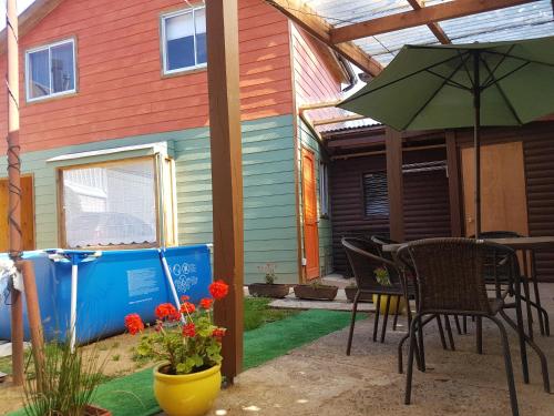 a patio with a table and chairs and an umbrella at Cabañas Emma in Osorno