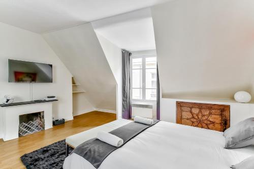 - une chambre blanche avec un grand lit et une cheminée dans l'établissement Love Nest in Saint-Michel, à Paris