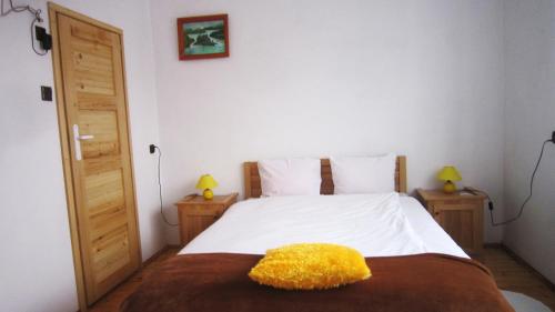 a bedroom with a bed with a yellow pillow on it at Królówka in Maków Podhalański
