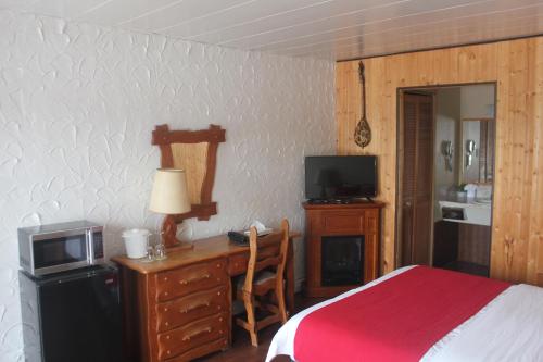 a bedroom with a bed and a desk with a microwave at Motel Des Pays D'En Haut in Val-David