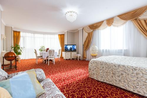 Habitación de hotel con cama y sala de estar. en Grand Hotel Uyut, en Krasnodar