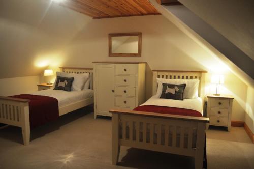 a bedroom with two beds and a dresser at The Old Coach House, Alltshellach Cottages in North Ballachulish
