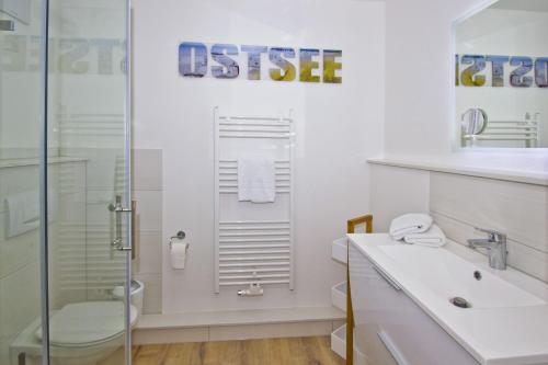 uma casa de banho branca com um chuveiro e um lavatório. em Haus Nordstrand - Tolle Ferienwohnung Ostseebad Göhren em Göhren