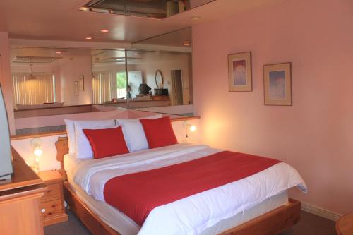 a bedroom with a large bed with red and white pillows at Motel Des Pays D'En Haut in Val-David