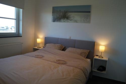 a bedroom with a bed with two lamps on it at Villa Jalina Sailors Beach in Nieuwpoort