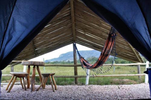 a hammock and two stools in a tent at CÉU DE AGARTHA Retiros e Vivências in Alto Paraíso de Goiás