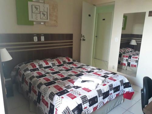 a bedroom with a bed with a quilt on it at San Marino Hotel in São José dos Campos