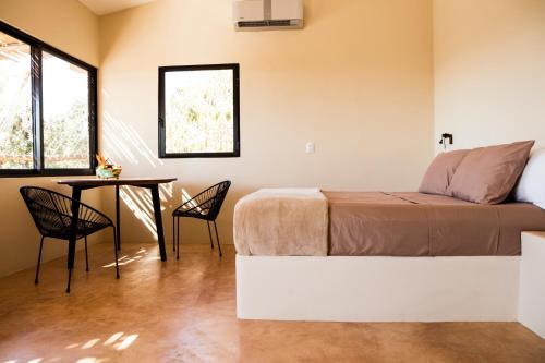 1 dormitorio con 1 cama, mesa y sillas en Casa Mono en San Agustinillo