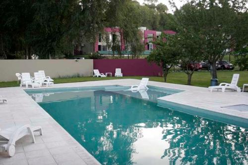 una piscina con sedie a sdraio bianche e una piscina di Hotel Sierra de los Padres a Sierra de los Padres