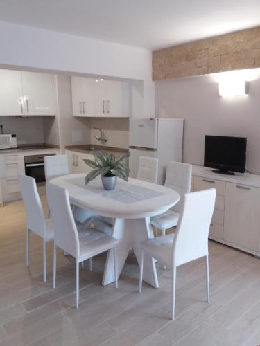 a white kitchen with a white table and chairs at Apartamento Torre Sant Salvador in Comarruga
