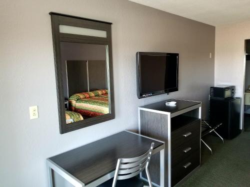 a hotel room with a mirror and a desk and a television at Executive Inn Pasadena in Pasadena