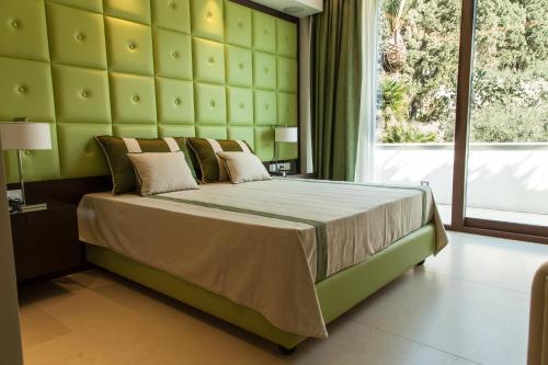 a bedroom with a large bed and a large window at Ngonia Bay Boutique Hotel in Milazzo