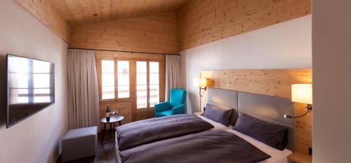una camera con letto e sedia blu di Adults Only Hotel Mulin - Das Erwachsenen-Hotel in den Bergen a Brigels