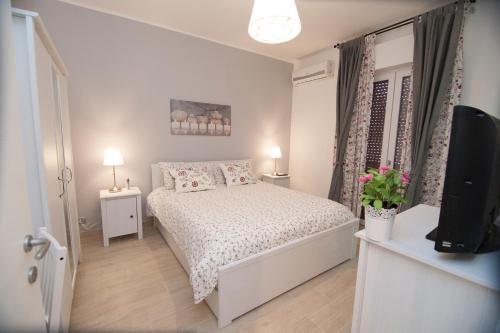 a white bedroom with a bed and a tv at Borgo Antico Home in Poggiorsini