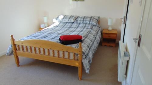 een slaapkamer met een bed met een houten frame en een rode deken bij Montclaire in Ballater