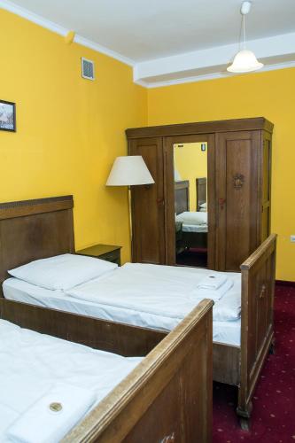 two beds in a room with a yellow wall at Hotel Karkonosze in Kamienna Góra