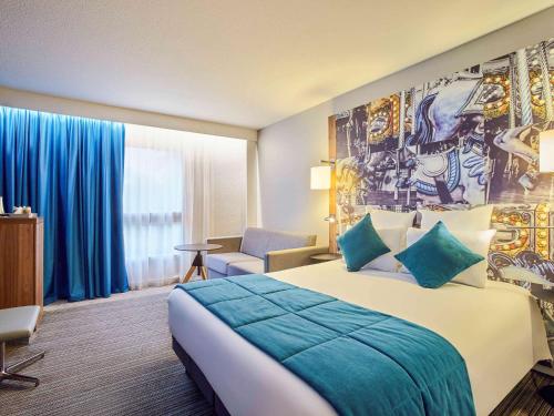 a hotel room with a large bed with blue sheets at Hotel Mercure Château de Fontainebleau in Fontainebleau