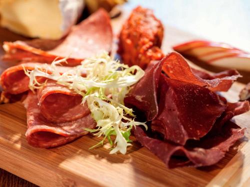 a wooden cutting board with meat and salad on it at Hotel ibis Lisboa Jose Malhoa in Lisbon