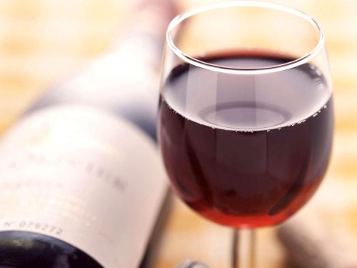 a glass of red wine next to a bottle of wine at Hotel ibis Lisboa Jose Malhoa in Lisbon