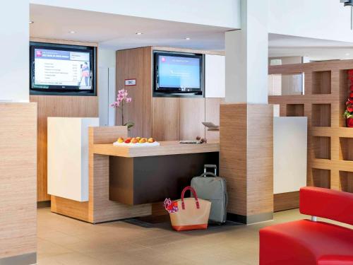 a lobby with a counter with a bowl of fruit at ibis Berlin Dreilinden in Kleinmachnow