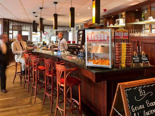 two men standing at a bar in a restaurant at ibis Hotel Brussels Expo Atomium in Brussels