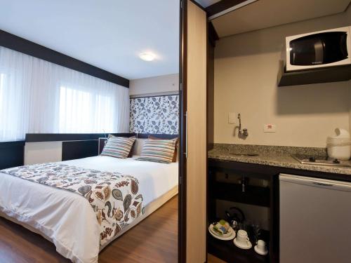 a hotel room with a bed and a kitchen at Mercure Sao Paulo Bela Vista in Sao Paulo