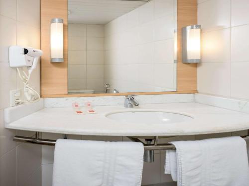 ein Badezimmer mit einem Waschbecken, einem Spiegel und Handtüchern in der Unterkunft ibis Belem Aeroporto in Belém