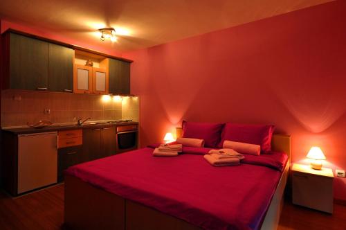 a red bedroom with a large red bed with two lamps at IWA CENTAR Apartments & Wellness in Vrnjačka Banja