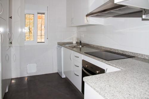 eine weiße Küche mit weißen Schränken und einem Waschbecken in der Unterkunft Playa centro in Villajoyosa