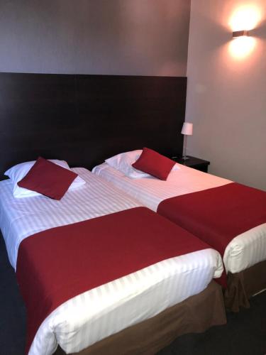 two beds in a hotel room with red and white sheets at Logis - Hôtel du Nord et Restaurant La Table d'Elisa in Compiègne