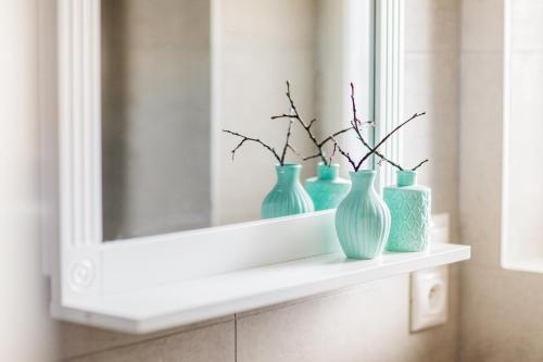 vier blaue Vasen auf einem Regal unter einem Spiegel in der Unterkunft Trendy Local Apartment in Prag