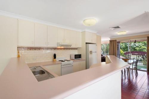 a kitchen with white cabinets and a counter top at Clifford Park Motor Inn in Toowoomba
