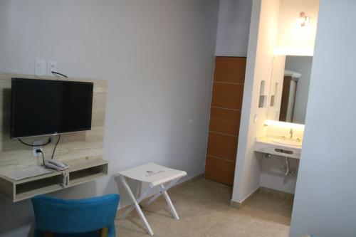 a room with a tv and a table and a sink at Ch Loreto Hotel Boutique in Ciudad de Loreto