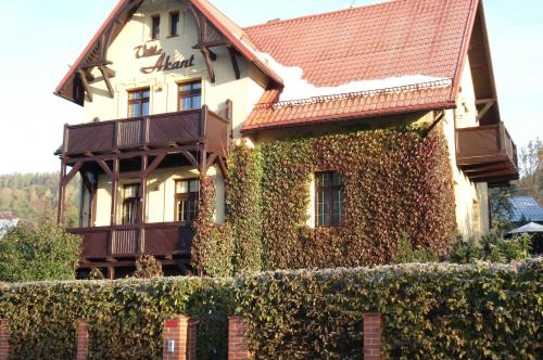 a house covered in ivy with a fence at Apartamenty Villa Akant in Piechowice