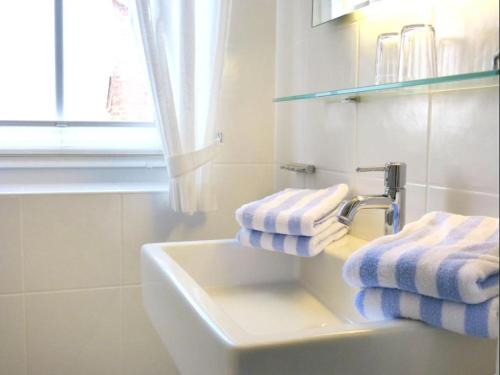 La salle de bains est pourvue d'un lavabo et de serviettes bleues et blanches. dans l'établissement *Südspitze 10 mit Meerblick*, à Wittdün