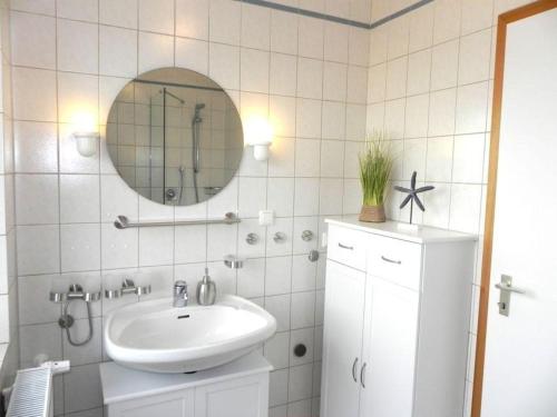 a white bathroom with a sink and a mirror at Ferienwohnung *Jessen´s Wattblick* in Wittdün