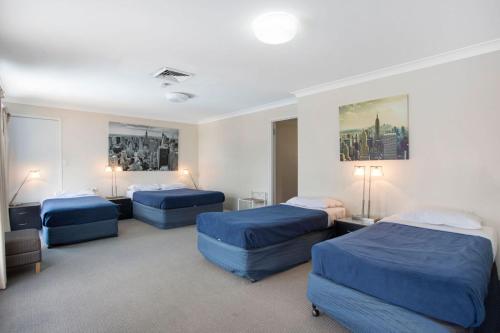 Habitación de hotel con 3 camas con sábanas azules en Clifford Park Motor Inn en Toowoomba
