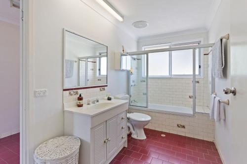 Baño blanco con lavabo y aseo en Clifford Park Motor Inn, en Toowoomba